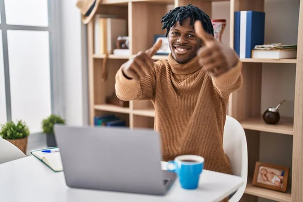 コンピュータのラップトップを使用して働いている恐ろしいロックを持つ若いアフリカ人男性は 手で積極的なジェスチャーを行うことを承認し 親指を上げて笑顔と成功のために幸せ 勝者のジェスチャー — ストック写真