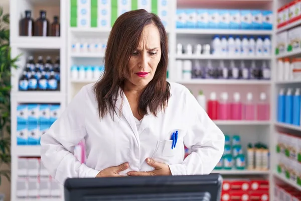 消化不良 痛みを伴う病気が体調不良のため 中年のブルネットの女性は胃の上に手で薬局で働いています キャッシュ コンセプト — ストック写真