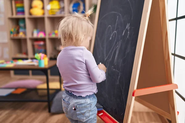 可爱的金发女学龄前学生在幼儿园的黑板上画画 — 图库照片