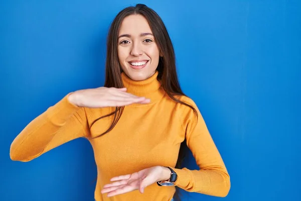 Young Brunette Woman Standing Blue Background Gesturing Hands Showing Big — стоковое фото