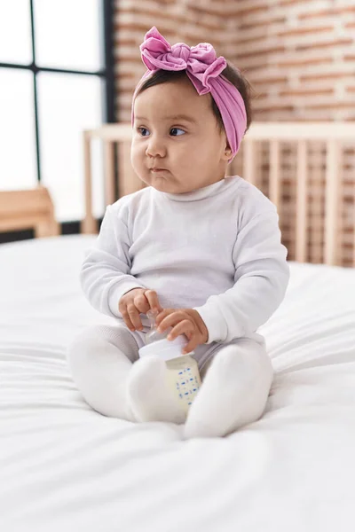 Adorable Hispanic Baby Sitting Bed Relaxed Expression Holding Feeding Bottle — Stock Photo, Image