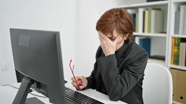 在图书馆用计算机学习的成熟的恐慌的女大学教师 — 图库照片
