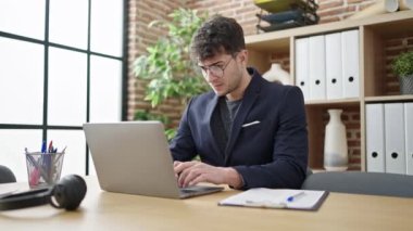 Genç İspanyol iş adamı ofisteki panoda dizüstü bilgisayar kullanıyor.