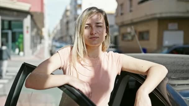 Jonge Blonde Vrouw Glimlachen Zelfverzekerd Leunend Auto Deur Straat — Stockvideo