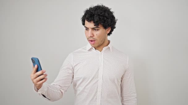 隔離された白い背景に驚きのスマートフォンを使用して若いラテン人のビジネスワーカー — ストック動画