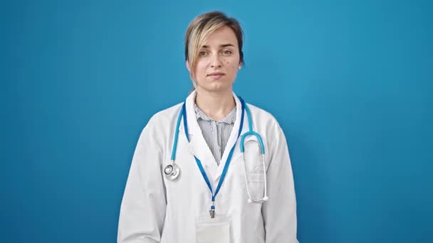 Νεαρή Ξανθιά Γυναίκα Γιατρός Στέκεται Χαρούμενη Έκφραση Πάνω Από Απομονωμένο — Αρχείο Βίντεο
