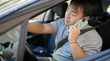  Akıllı telefondan konuşuyor. Sokakta arabada oturuyor.