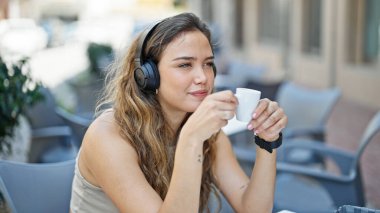 Genç ve güzel İspanyol kadın kahve dükkanının terasında müzik dinliyor.