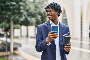 Afro-Amerikalı yönetici akıllı telefon kullanıyor. Sokakta kahve içiyor.