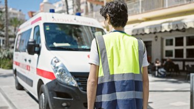 Genç İspanyol hemşire ambulansın arkasında dikiliyor.