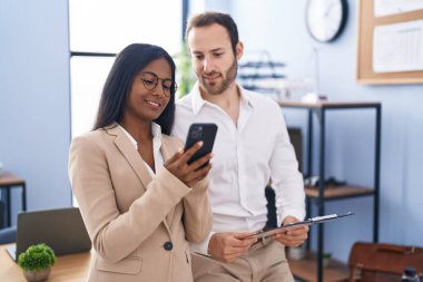 Man and woman business workers using smartphone reading document at office