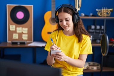 Young woman musician composing song at music studio