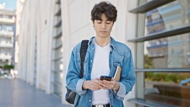 Genç İspanyol öğrenci üniversitede rahat bir ifadeyle akıllı telefon kullanıyor.