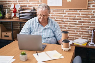 Orta yaşlı, kır saçlı, elinde kahve tutan bir iş adamı.