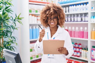 Eczanede çalışan akıllı telefonu kullanan Afrikalı Amerikalı kadın eczacı.