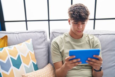 Genç İspanyol ergen evdeki kanepede oturmuş dokunmatik bir şekilde video izliyor.