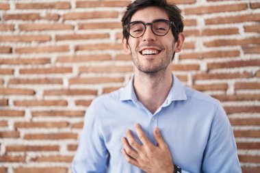 Duvarın arkasında dikilen Latin asıllı genç adam gülümsüyor ve kahkahalarla gülüyor.. 