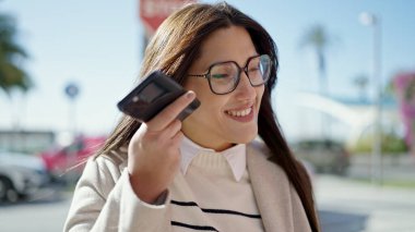 Genç ve güzel İspanyol kadın gülümsüyor. Caddedeki akıllı telefondan kendine güvenen bir sesli mesaj dinliyor.