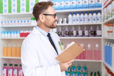 Middle age man pharmacist reading book at pharmacy