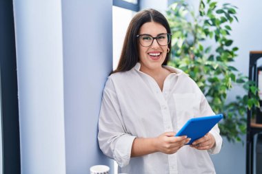 Young hispanic woman business worker using touchpad working at office