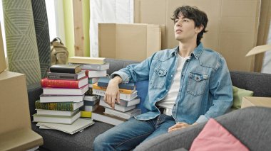 Genç İspanyol adam yeni evindeki kanepede dinleniyor.