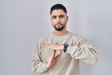 Tecrit edilmiş arka planda duran genç yakışıklı adam. Elleriyle jest yapıyor, hayal kırıklığına uğramış ve ciddi bir yüz ifadesi takınıyor. 