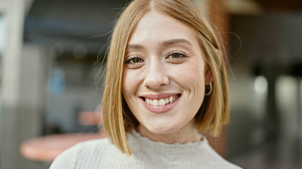 Young blonde woman smiling confident standing at coffee shop terrace
