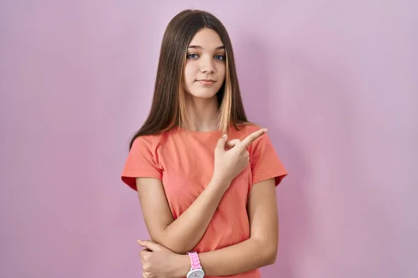 少女站在粉色的背景上 手指头指向广告的侧面 严肃而沉着 — 图库照片