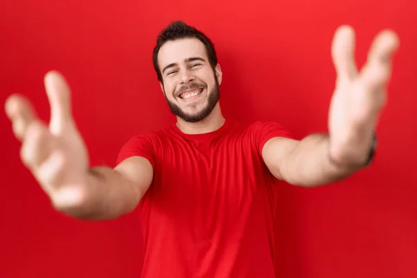 Gündelik Kırmızı Tişört Giyen Genç Spanyol Adam Kameraya Bakıp Sarılmak — Stok fotoğraf