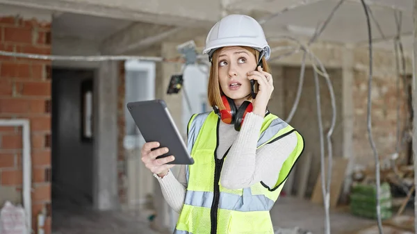 年轻的金发女建筑师在建筑工地用智能手机看着触摸板说话 — 图库照片