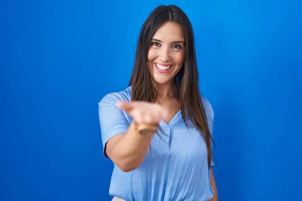 Jonge Brunette Vrouw Staande Blauwe Achtergrond Glimlachend Vrolijk Aanbieden Palm — Stockfoto