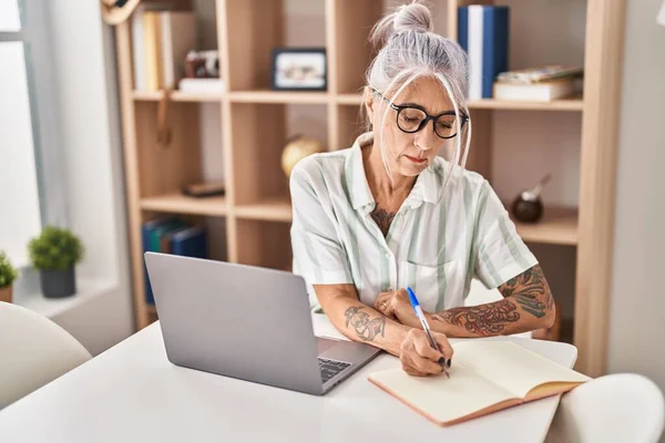 Mulher Cabelos Grisalhos Meia Idade Escrevendo Notebook Usando Laptop Casa — Fotografia de Stock