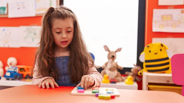 Adorable Hispanic Girl Playing Maths Puzzle Game Sitting Table Kindergarten — Stok fotoğraf