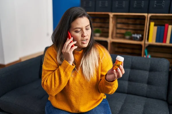 Young Beautiful Size Woman Talking Smartphone Holding Pills Home — Stock fotografie