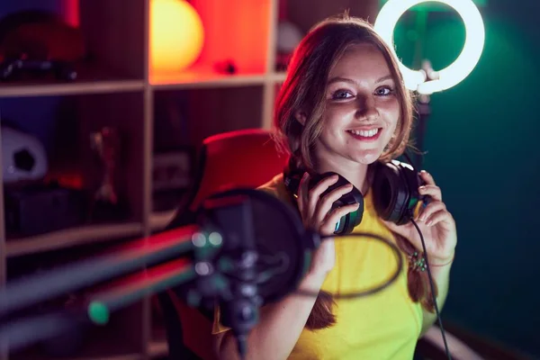 Joven Mujer Rubia Streamer Sonriendo Confiado Sosteniendo Auriculares Sala Juegos —  Fotos de Stock