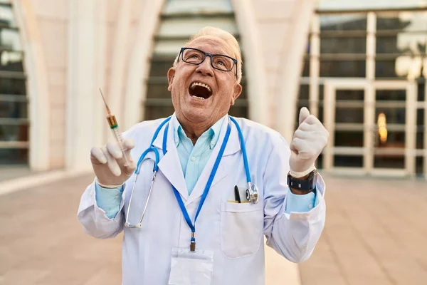 Starszy Lekarz Siwymi Włosami Trzymając Strzykawkę Krzycząc Dumny Świętując Zwycięstwo — Zdjęcie stockowe