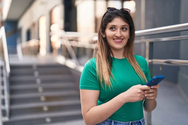 Молодая Латиноамериканка Уверенно Улыбается Используя Смартфон Улице — стоковое фото