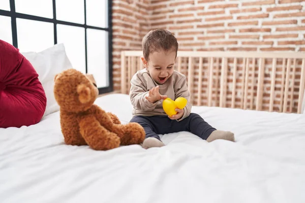 可爱的惊慌失措的男孩抱着鸭玩具坐在卧室的床上 — 图库照片