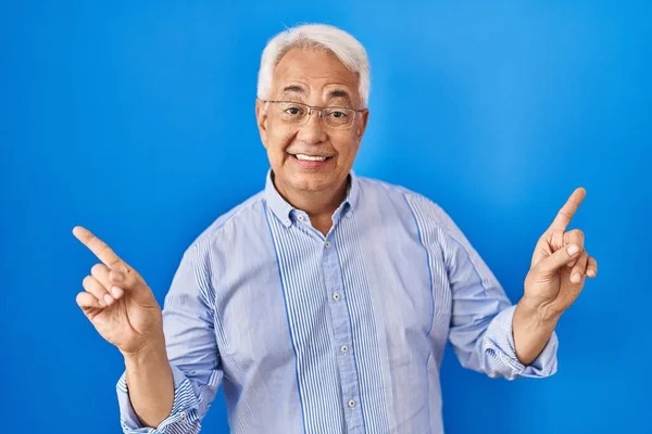 西班牙裔老人戴着眼镜 带着自信的微笑 用手指指向不同的方向 复制广告空间 — 图库照片