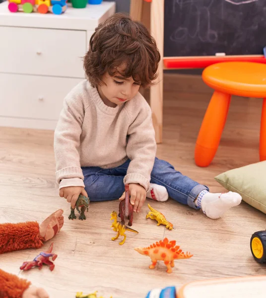 愛らしいHispanic男の子遊びとともに恐竜のおもちゃ座っています床に幼稚園 — ストック写真