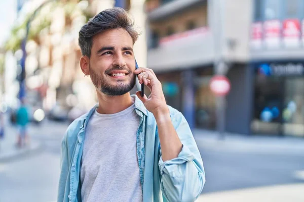 年轻的惊慌失措的男人在街上用智能手机自信地微笑着 — 图库照片