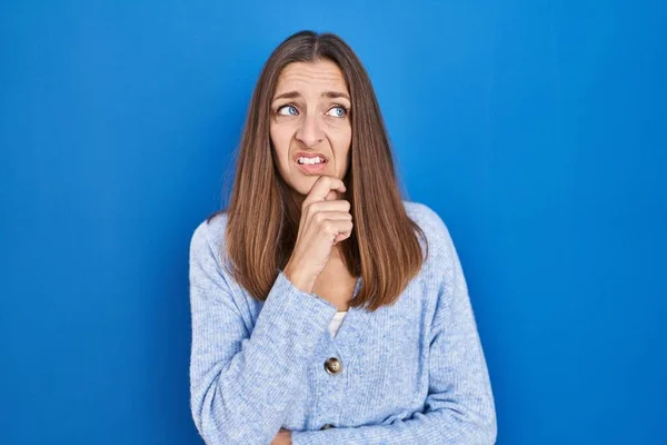 Jovem Mulher Sobre Fundo Azul Pensando Preocupado Com Uma Pergunta — Fotografia de Stock