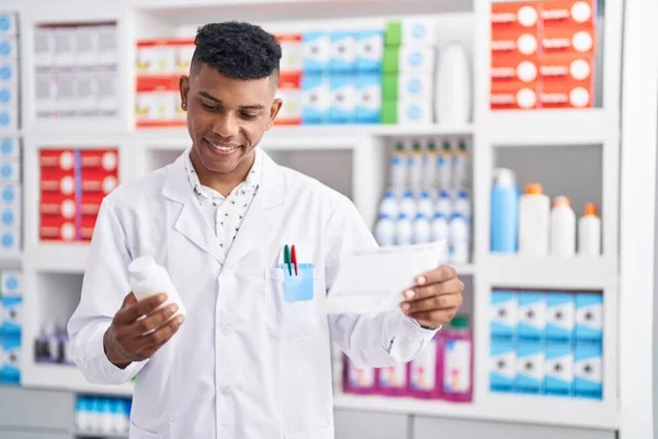 Young Latin Man Pharmacist Holding Pills Bottle Reading Prescription Pharmacy —  Fotos de Stock