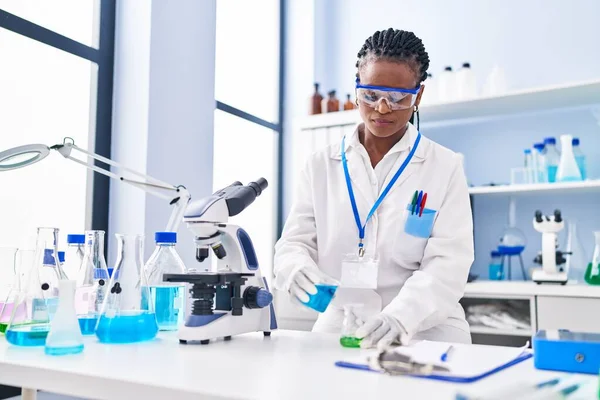 アフリカ系アメリカ人女性科学者は自信を持って液体を注ぐ笑みを浮かべて実験室でチューブ — ストック写真