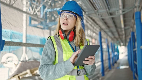 Young blonde woman builder using touchpad at street
