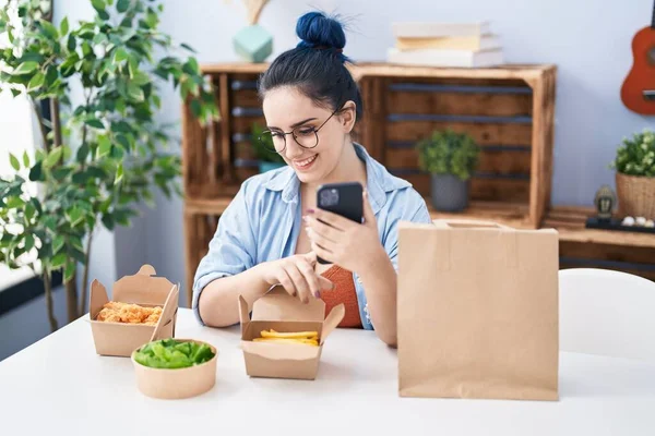 Young Caucasian Woman Eating Take Away Food Using Smartphone Home — ストック写真