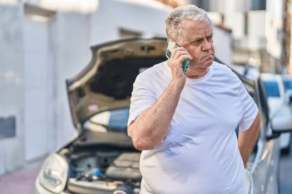 中年白发男子在街上用智能手机与汽车保险交谈 — 图库照片