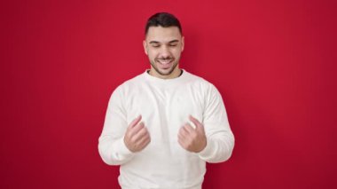 İspanyol asıllı genç adam, kendine güveni tam kırmızı arka planda, kazanan yüz ifadesiyle duruyor.