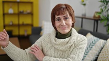 Olgun İspanyol kadın gülümsüyor. Kendine güveni tam. Koluyla güçlü hareketler yapıyor.