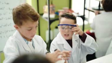 Laboratuvar sınıfında mikroskop kullanan bir grup çocuk akıllı telefon kullanıyor.